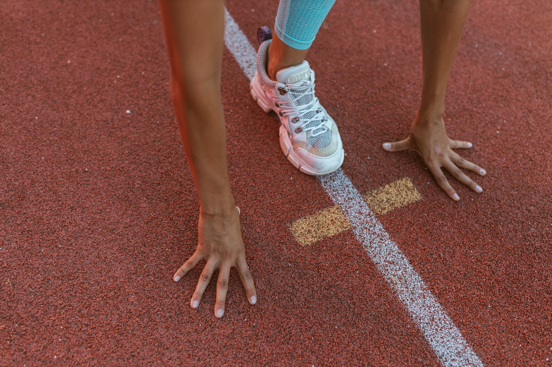 individual on racing track getting ready to run for fitness